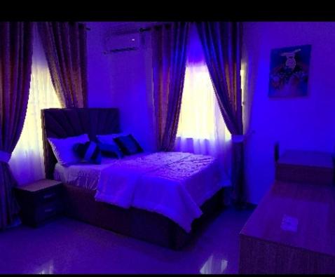 purpurowa sypialnia z łóżkiem i oknem w obiekcie Specfield Court And Apartment Sun City 