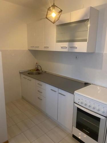 een keuken met witte kasten, een wastafel en een fornuis bij Vlada apartment 2 in Vranje