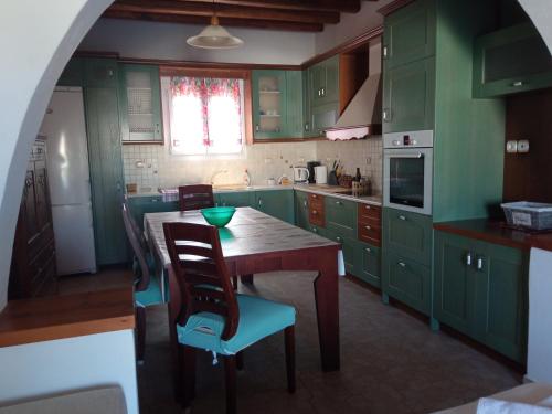 een keuken met groene kasten en een tafel en stoelen bij Home Sweet Home Milos in Triovasálos