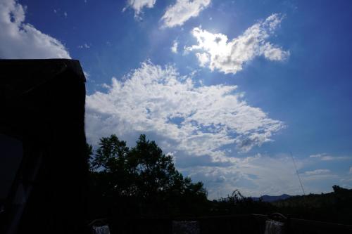 a blue sky with clouds and a tree at Rustic River & Bush Escape in Buffelspoort
