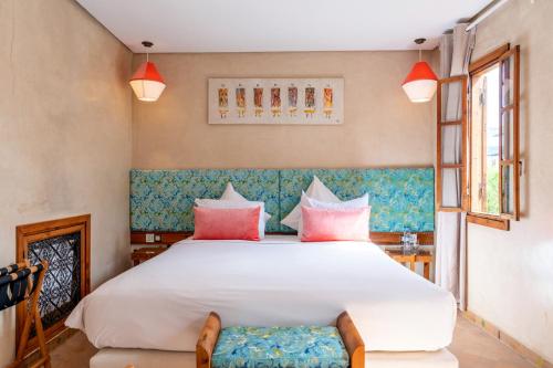 a bedroom with a large white bed with pink pillows at Riad Kalaa in Rabat