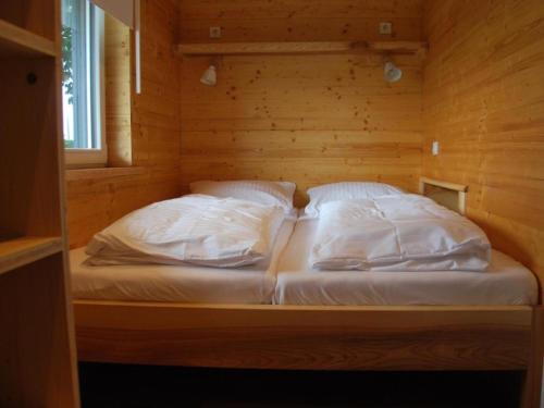 a bed in a wooden room with two pillows at Ferienhaus Das Kleine Paradies in Liebenau
