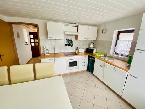 a kitchen with white cabinets and a white refrigerator at KAPITÄNS HUS 1 - Sauna, großer Garten, 400m zum Strand in Graal-Müritz