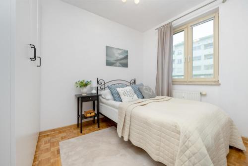 a white bedroom with a bed and a window at Bukowińska Apartments with Balcony and Parking and Swimming Pool by Renters in Warsaw