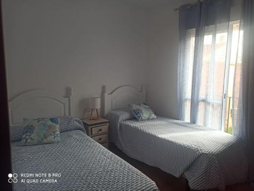 sypialnia z 2 łóżkami pojedynczymi i oknem w obiekcie Unifamiliar 3 dormitorios Casa Mar w mieście Islantilla