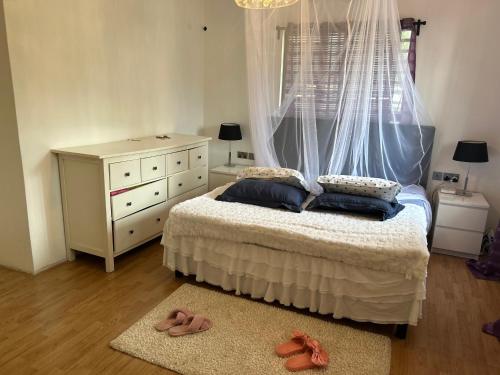 um quarto com uma cama, uma cómoda e chinelos em Cinnamon House em Kisumu