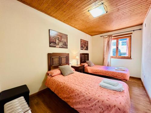a bedroom with two beds and a wooden ceiling at Apartamento Sant Climent Timmo in Taüll