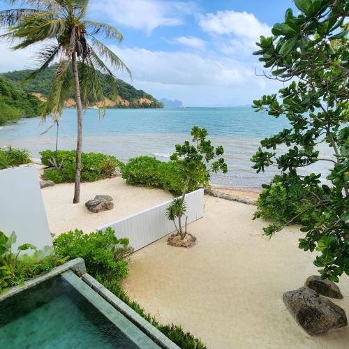a swimming pool on a beach next to the ocean at Luxury Beachfront AMANA Villa 4 Br at Ta-Ke Residence A in Phuket