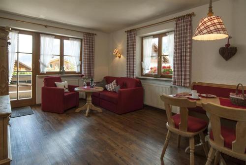 a living room with red chairs and a table at Landhaus Exclusiv in Bolsterlang