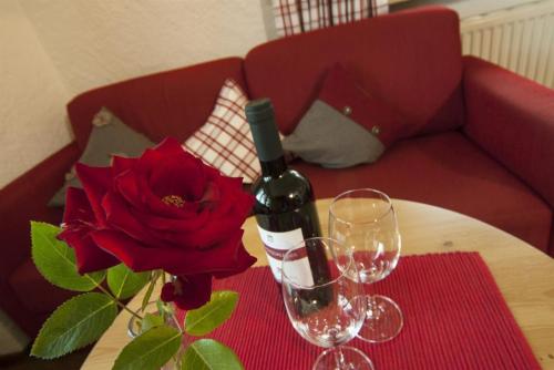 a bottle of wine and two glasses on a table with a rose at Landhaus Exclusiv in Bolsterlang