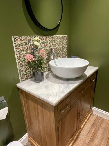 a bathroom with a sink and flowers on a counter at The Dairy Scratby in Scratby