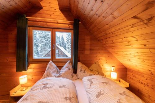 a bedroom in a log cabin with a bed and a window at Almhütte Hebalm mit Whirpool in Pack
