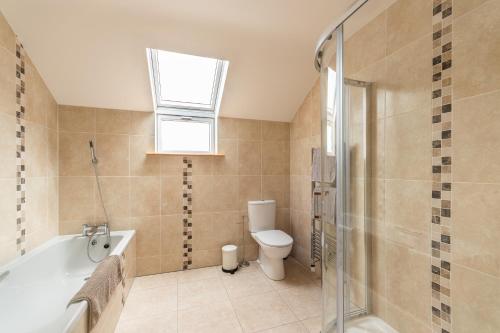 een badkamer met een bad, een toilet en een raam bij Luxury 4 bedroom holiday home overlooking the sea on Valentia Island in Knights Town