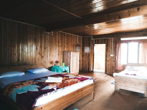 1 dormitorio con 1 cama grande en una habitación de madera en Neora valley eco hut's Kolakham, en Lava