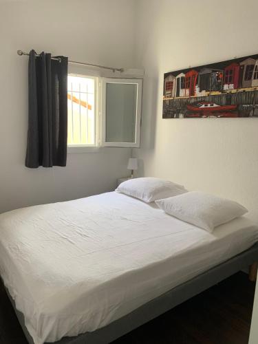 une chambre avec un lit blanc avec une fenêtre dans l'établissement Charmante petite maison à proximité de la plage, à Palavas-les-Flots