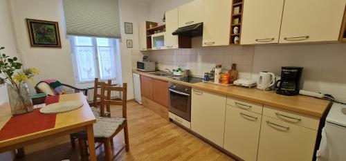une cuisine avec des placards blancs, une table et une salle à manger dans l'établissement APARTMA DOMENIKA, à Ptuj