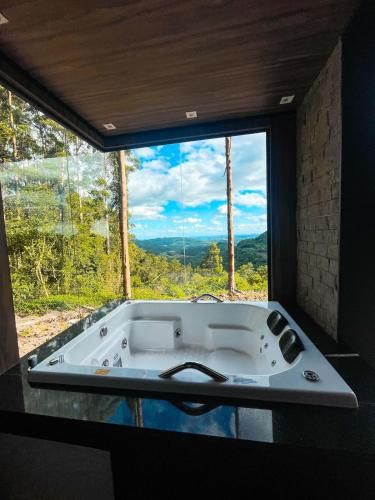 uma banheira num quarto com uma grande janela em Cabana Vista Bela em São Salvador