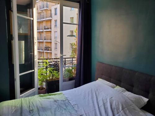 a bedroom with a bed and a window with a view at Bel appartement à Clichy sur Seine in Clichy