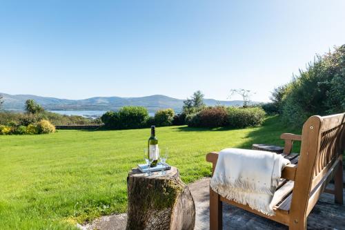 a table with a bottle of wine on top of a tree stump at Stylish and spacious home with sea & mountain views in Templenoe