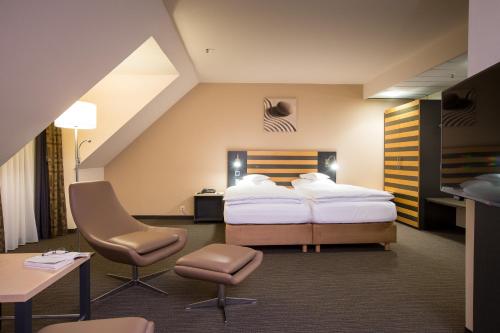 Pokój hotelowy z łóżkiem, biurkiem i krzesłami w obiekcie Lindner Hotel Frankfurt Hochst, part of JdV by Hyatt w Frankfurcie nad Menem