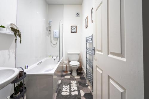 a bathroom with a tub and a toilet and a sink at Coatbridge Apartment in Coatbridge