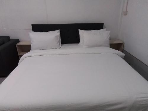 a large white bed with white sheets and pillows at The Rock Coco Villa in Ban Laem Pom