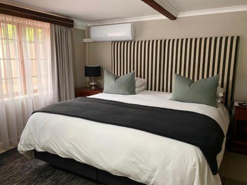 Un dormitorio con una gran cama blanca con almohadas verdes. en La Casa Guest House, en Bloemfontein