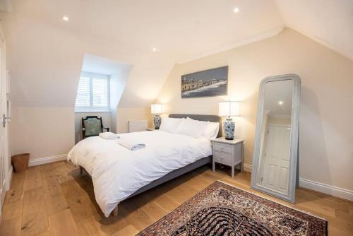a bedroom with a large white bed and a mirror at Fromus Rise, Saxmundham in Saxmundham