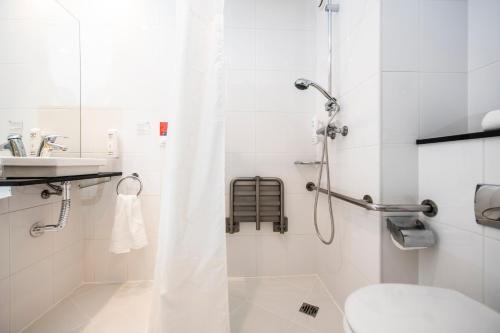 uma casa de banho com um chuveiro, um WC e um lavatório. em Holiday Inn Express Sant Cugat, an IHG Hotel em Sant Cugat del Vallès