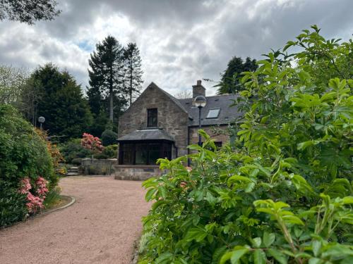 uma antiga casa de pedra com um jardim em frente em Awakening Alchemy Retreat Centre em Inverurie