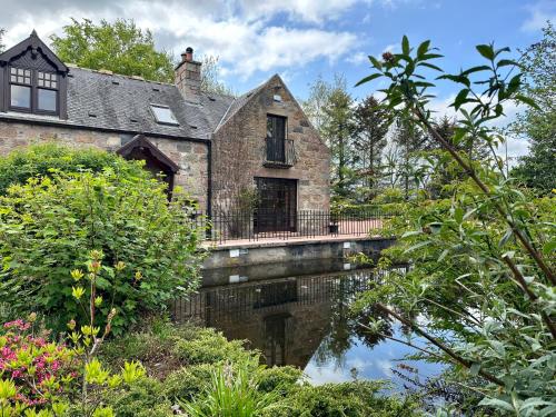 an old stone house with a bridge over a river at Awakening Alchemy Retreat Centre in Inverurie