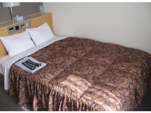 Akashi Castle Hotel - Vacation STAY 83574 في أكاشي: سرير في غرفة الفندق وعليه بطانية