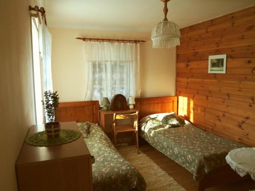 a bedroom with two beds and a table and a window at Domek Zapiecek in Białowieża