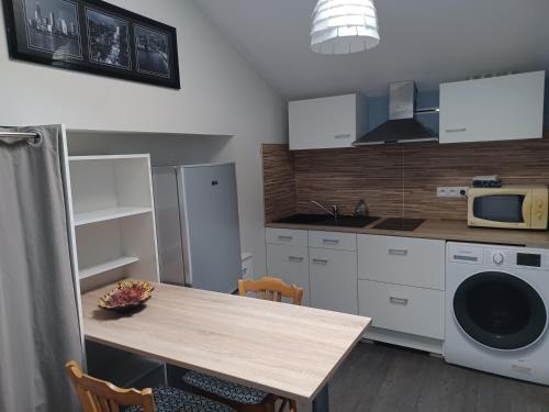 une cuisine avec une table en bois et un micro-ondes dans l'établissement Chambre d'Hôtes La Rose des Vents, à Sathonay-Camp