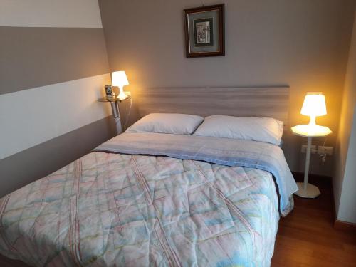 un letto in una camera da letto con 2 lampade e un copriletto di Elegant and modern Apartment "Le Fontane" Moncalieri a Moncalieri