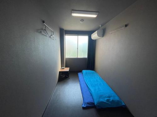 大阪市にあるHotel Aiwa for men's onlyの青いベッドと窓が備わる客室です。