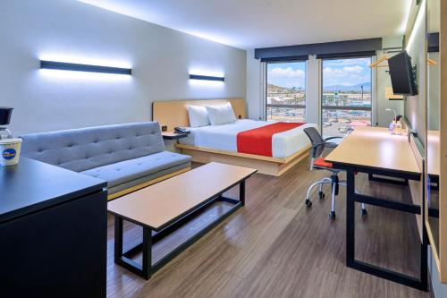 um quarto de hotel com uma cama e um sofá em City Express by Marriott Piedras Negras em Piedras Negras