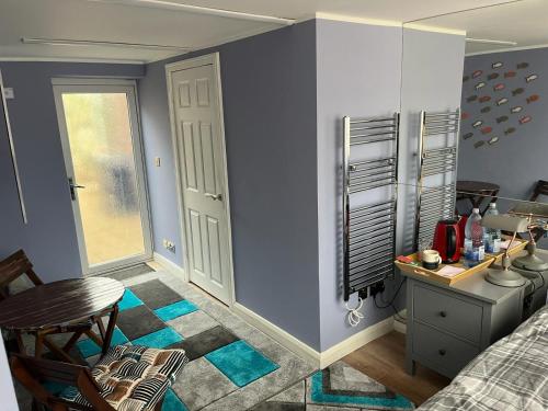 1 dormitorio con paredes azules, mesa y silla en Cozy Guest Room in High Barnet (London) with Private Entrance and Small Terrace, en Londres