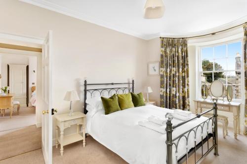 a bedroom with a large white bed with green pillows at Milton House in Leyburn