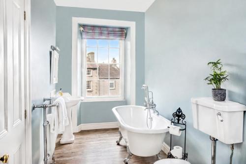 a bathroom with a tub and a sink and a window at Milton House in Leyburn