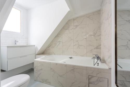 La salle de bains blanche est pourvue d'une baignoire et de toilettes. dans l'établissement Le Marais, Romantic loft apartment! min 31 nights from June to December, à Paris