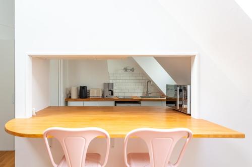 une cuisine avec une table en bois et deux chaises blanches dans l'établissement Le Marais, Romantic loft apartment! min 31 nights from June to December, à Paris