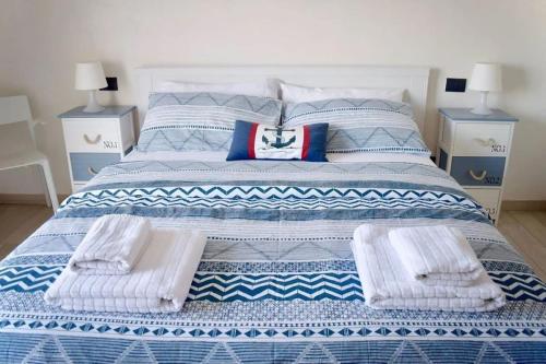 a large bed with blue and white sheets and pillows at Harbor Houses II in Marzamemi