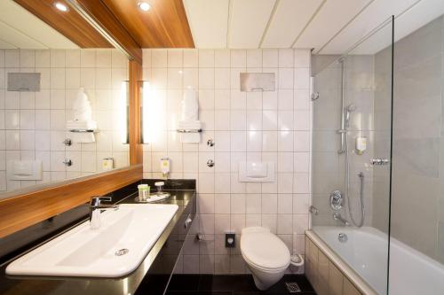 ein Badezimmer mit einem Waschbecken, einem WC und einer Badewanne in der Unterkunft Lindner Hotel Frankfurt Hochst, part of JdV by Hyatt in Frankfurt am Main