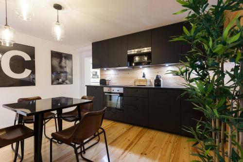 リスボンにあるMY LX FLAT Castle Alfama Studioのキッチン(黒いキャビネット、テーブル、椅子付)
