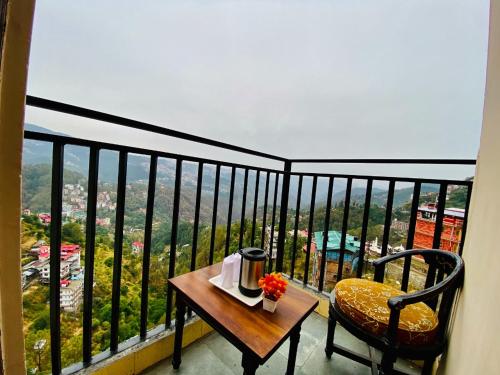 a balcony with a table and a chair and a view at Aachman velly view with terrace in Shimla