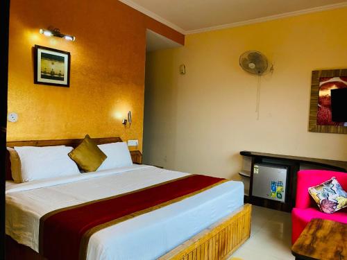 1 dormitorio con 1 cama grande y 1 silla rosa en Aachman velly view with terrace, en Shimla