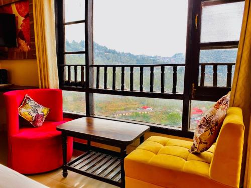 a living room with a couch and a table and a large window at Aachman velly view with terrace in Shimla