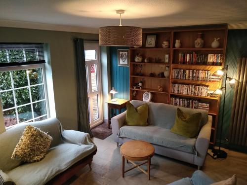 a living room with two couches and a book shelf at The Whimsy 2 bedroom cottage in National Forest, private parking & garden in Blackfordby