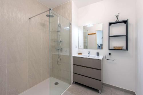 ein Bad mit einer Glasdusche und einem Waschbecken in der Unterkunft Appartement contemporain dans résidence de standing, tout confort in Saint-Elme
